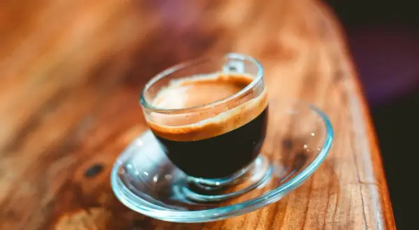 En liten kopp espresso ristretto med krämig crema på ett träbord.