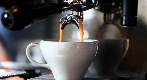 En liten espresso rinner ner i en vit kopp från en espressomaskin.