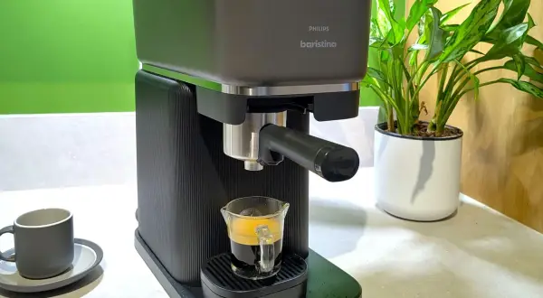 En Philips Baristina espressomaskin brygger en perfekt shot kaffe till espressomaskin. En grön vägg och en krukväxt i bakgrunden.