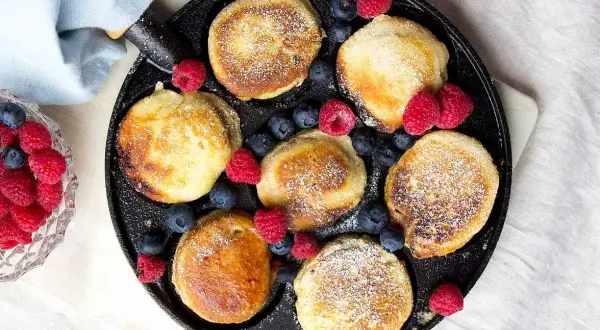 Små, gyllene krabbelurer i stekpanna, pudrade med florsocker och dekorerade med färska hallon och blåbär. Ett härligt recept för frukost eller fika.