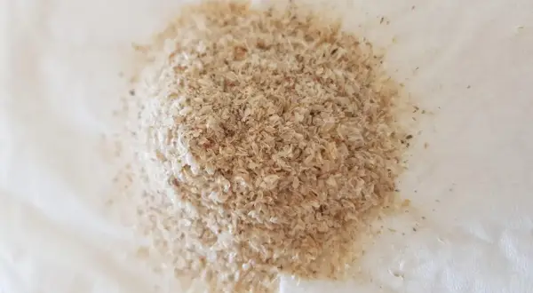 En hög med fiberhusk psyllium på vitt papper.
