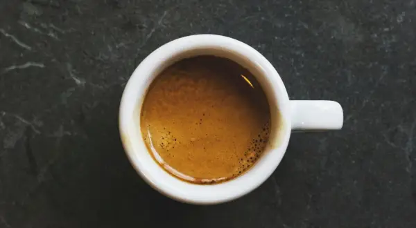 En vit kopp med en gyllene espresso, en perfekt start på dagen med äkta italienska kaffesorter.