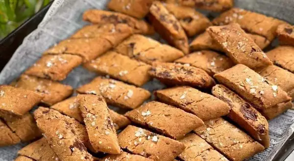 En hög med hembakade kolakakor med chokladbitar, strösslade med flingsalt. Perfekt för ett kolakakor recept!