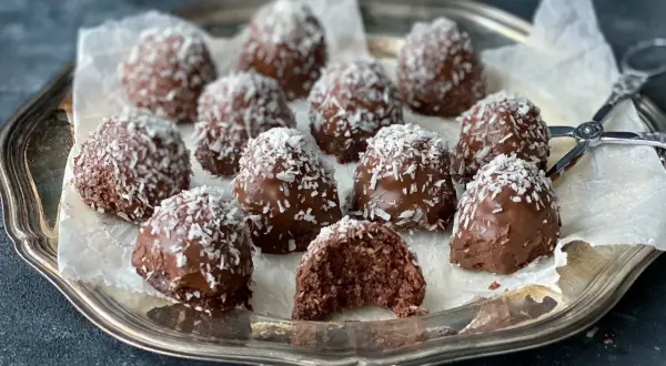 Chokladiga havrebollar, perfekta för ett snabbt havrebollar recept. Garnerade med kokosflingor på en silverbricka.