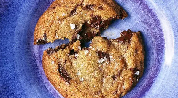 En chokladchipkaka, delad, med smält choklad som rinner ut. Strössel av flingsalt.