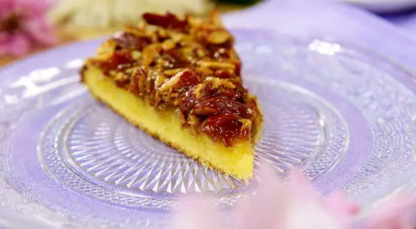 En bit glutenfri toscakaka med mandeltosca på en vacker glasfat.