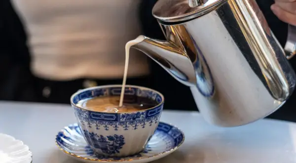 Grädde hälls i en vacker blåvit kaffekopp. Kanske en del av svaret på vilket land dricker mest kaffe?