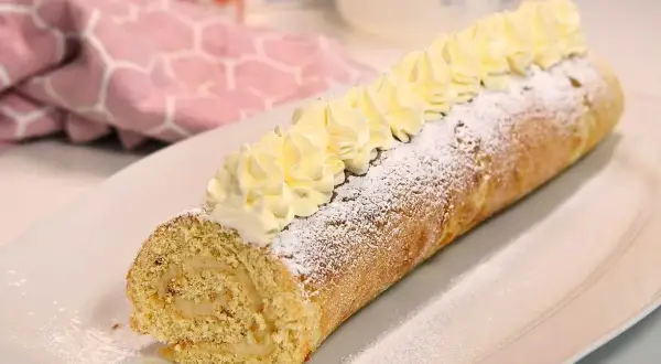 En härlig semmelrulltårta glutenfri, pudrad med florsocker och toppad med grädde. Perfekt för fikat!