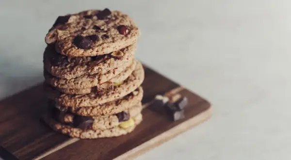 En hög med glutenfria småkakor från Lailas, med chokladbitar och nötter, ligger på en träskärbräda.