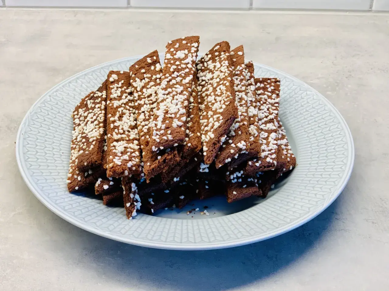En hög med choklad snittar, toppade med pärlsocker, ligger på en ljusblå tallrik.