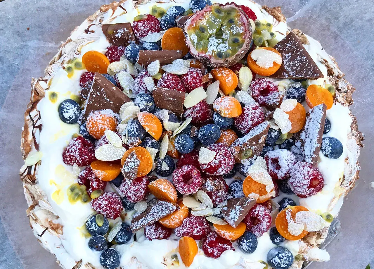 En vacker pavlova med bär, choklad och passionsfrukt. Ett perfekt pavlova recept för sommaren.