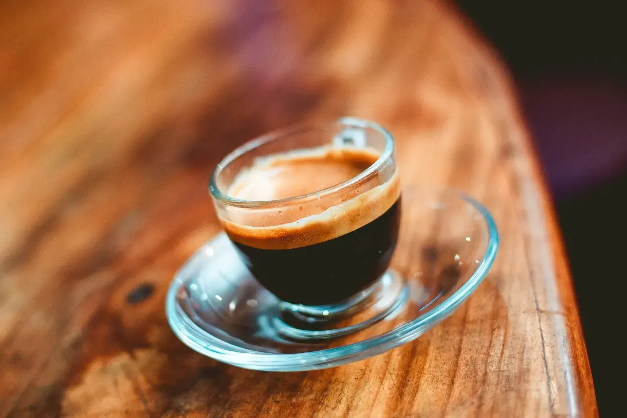 En liten kopp espresso ristretto med krämig crema på ett träbord.