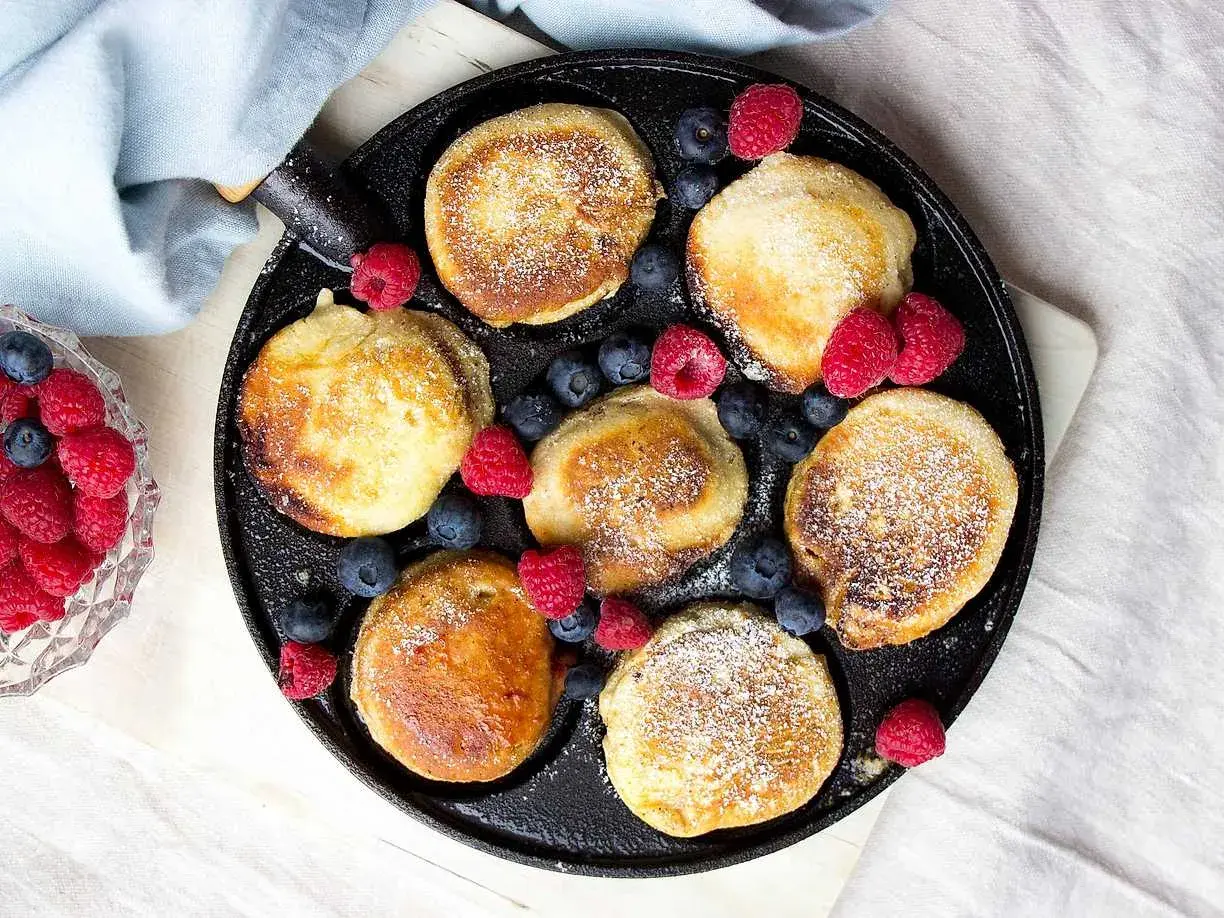 Små, gyllene krabbelurer i stekpanna, pudrade med florsocker och dekorerade med färska hallon och blåbär. Ett härligt recept för frukost eller fika.