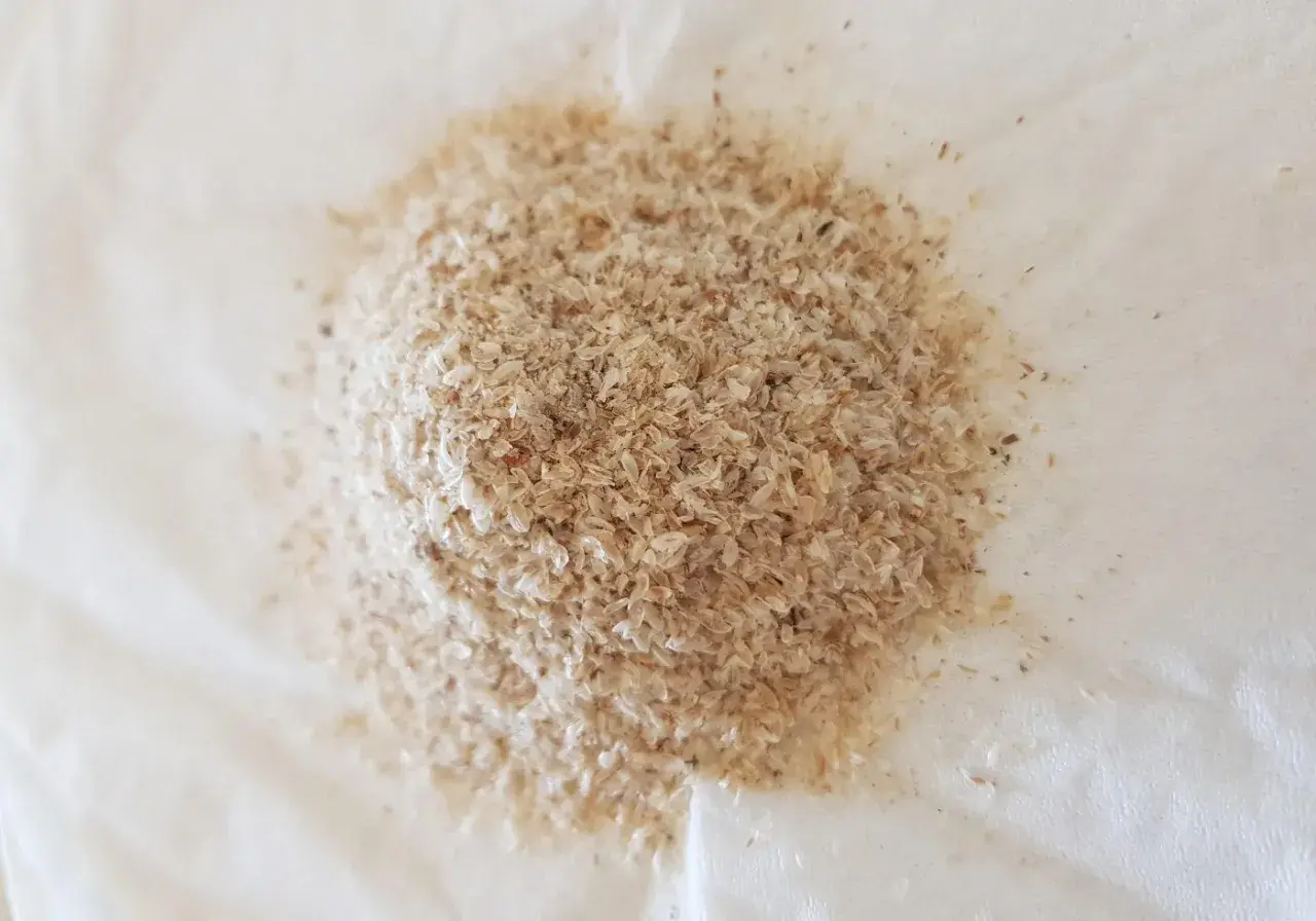 En hög med fiberhusk psyllium på vitt papper.