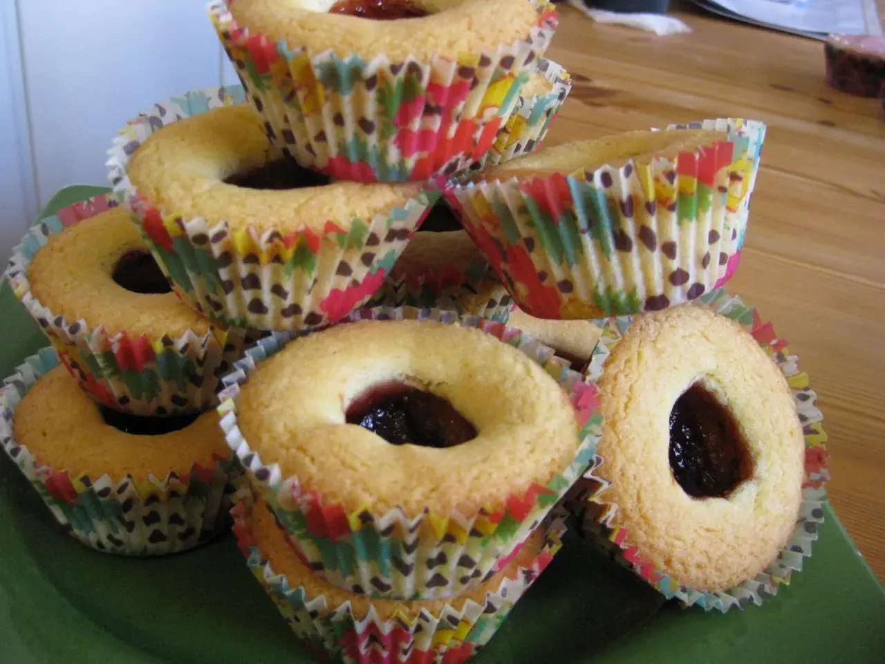 En hög med hallongrottor i färgglada muffinsformar, redo att avnjutas.