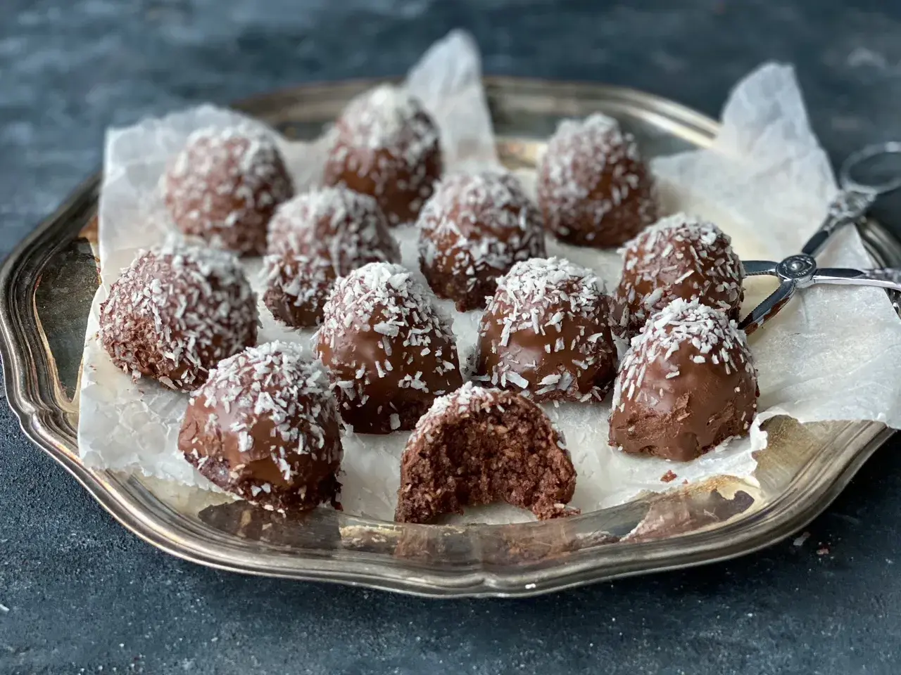 Chokladiga havrebollar, perfekta för ett snabbt havrebollar recept. Garnerade med kokosflingor på en silverbricka.