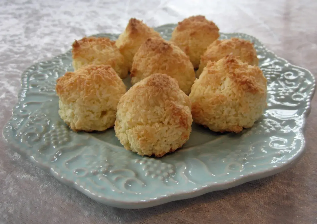 En tallrik med nybakade kokostoppar, perfekta för ett enkelt kokostoppar recept. De gyllene topparna ser inbjudande ut.