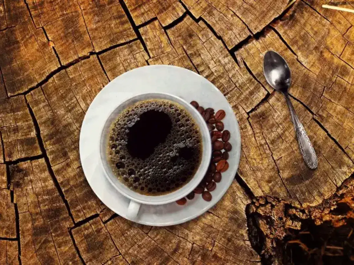 En kopp kaffe med bönor och en sked på en trädstam. Undrar du hur mycket koffein i en kopp kaffe?