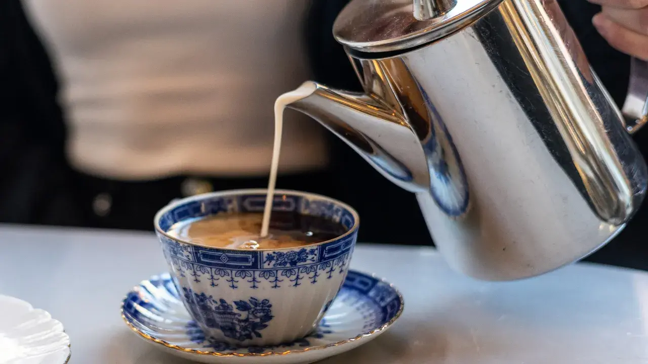 Grädde hälls i en vacker blåvit kaffekopp. Kanske en del av svaret på vilket land dricker mest kaffe?
