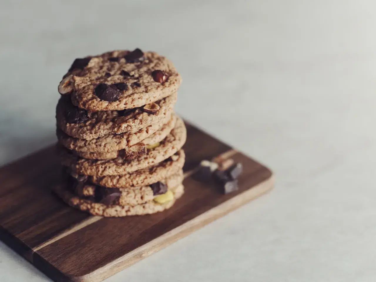 En hög med glutenfria småkakor från Lailas, med chokladbitar och nötter, ligger på en träskärbräda.