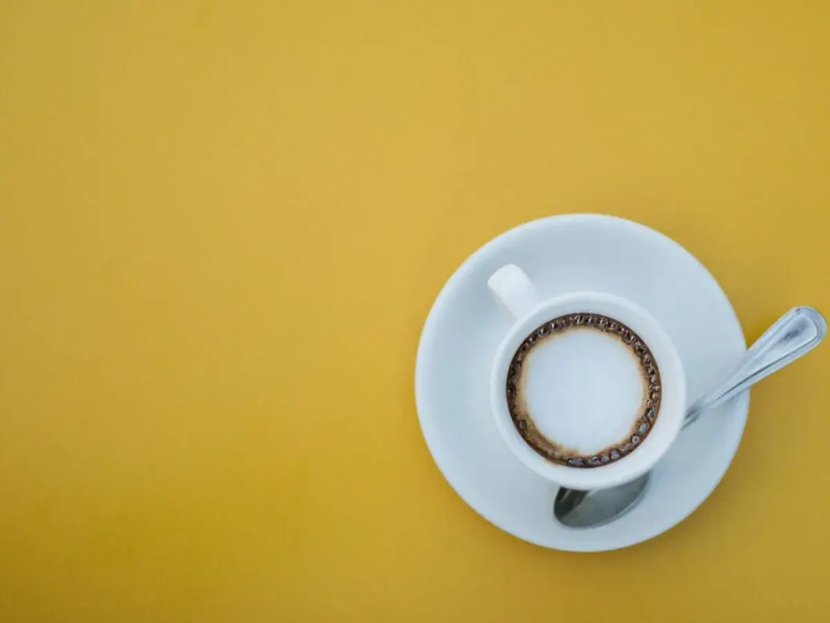 En kopp kaffe macchiato med skum och en ring av kaffe på en gul bakgrund. Perfekt för ett enkelt macchiato recept.