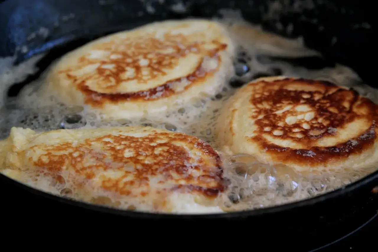 Tre gyllene krabbelurer glutenfria steks i en panna med bubblande sm&ouml;r.