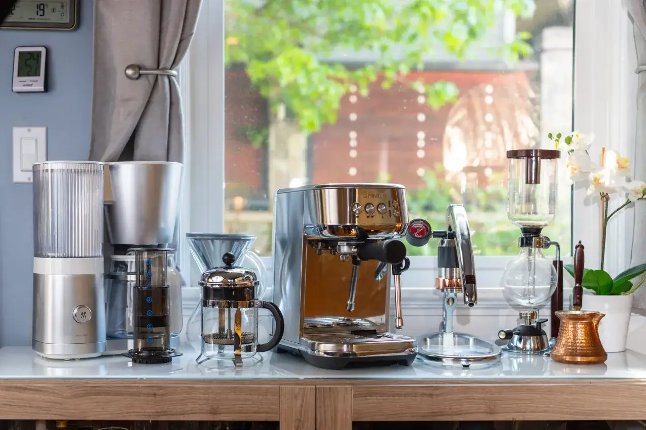 En samling kaffebryggare, inklusive en espressomaskin och en fransk press, redo att brygga kaffe manuellt.