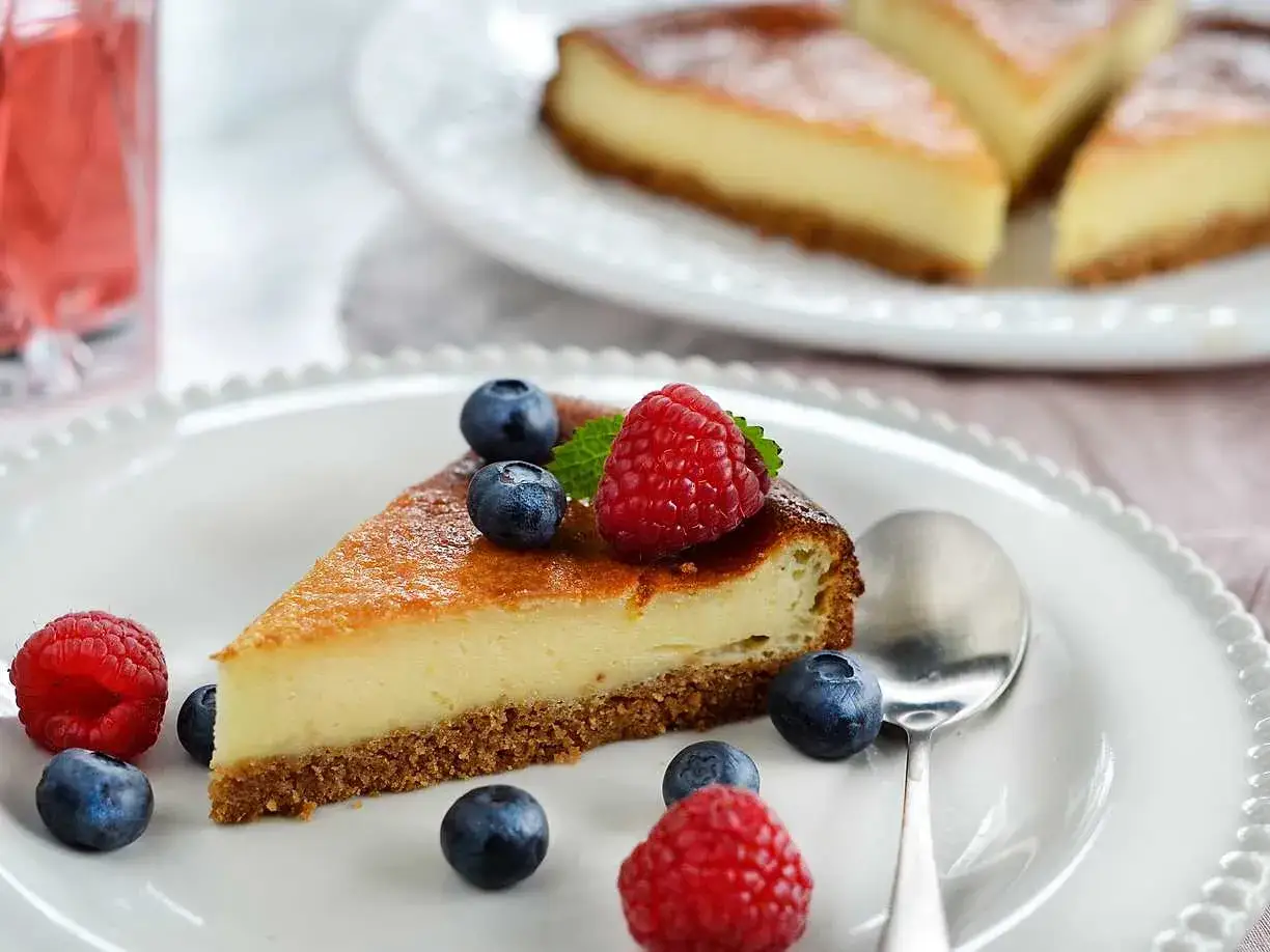 En bit cheesecake med digestivekex botten, toppad med b&auml;r. Ett perfekt recept f&ouml;r hembakad cheesecake.