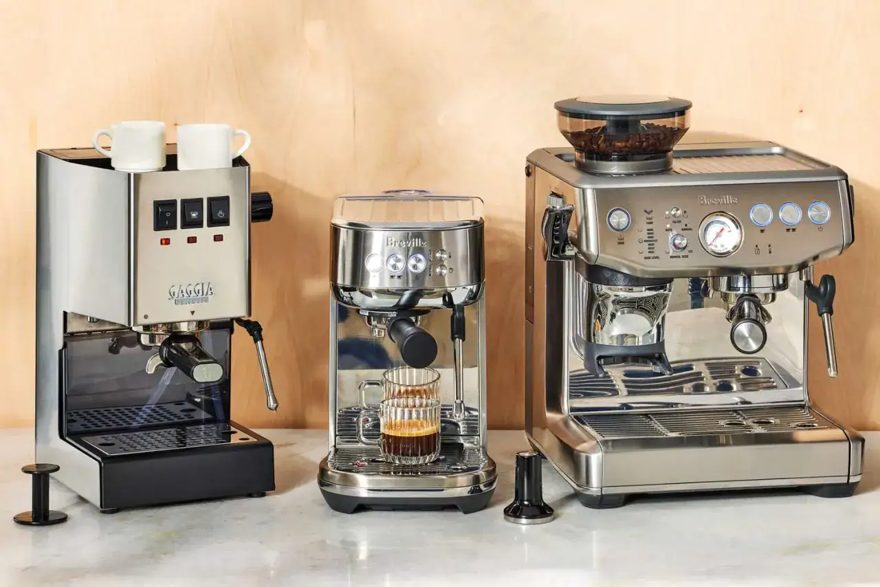 Tre espressomaskiner i metall. En liten kopp med enkel espresso st&aring;r redo.