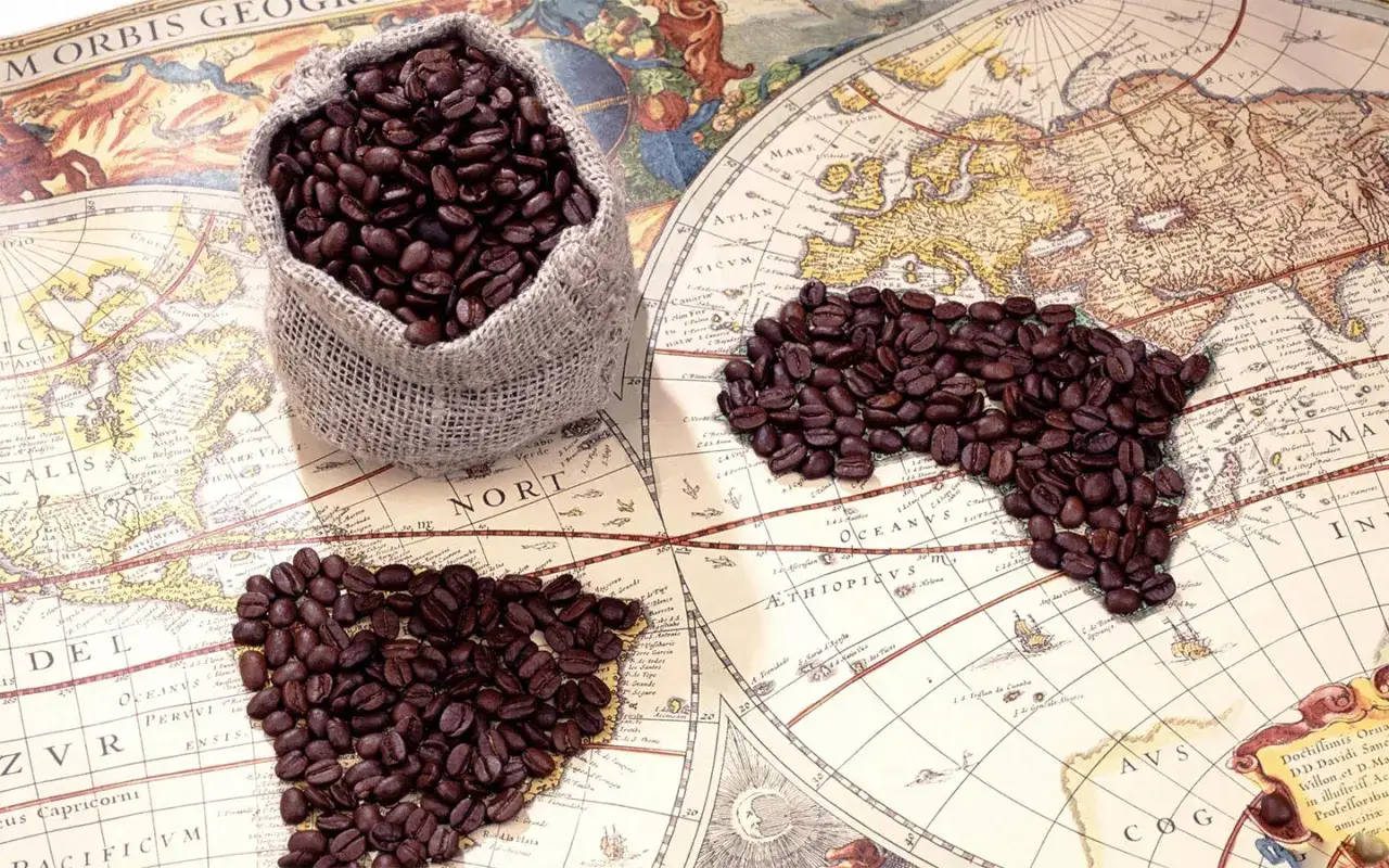 Kaffebönor i en säck och formade som ett hjärta och Afrika på en gammal världskarta, som symboliserar kaffe ursprung.