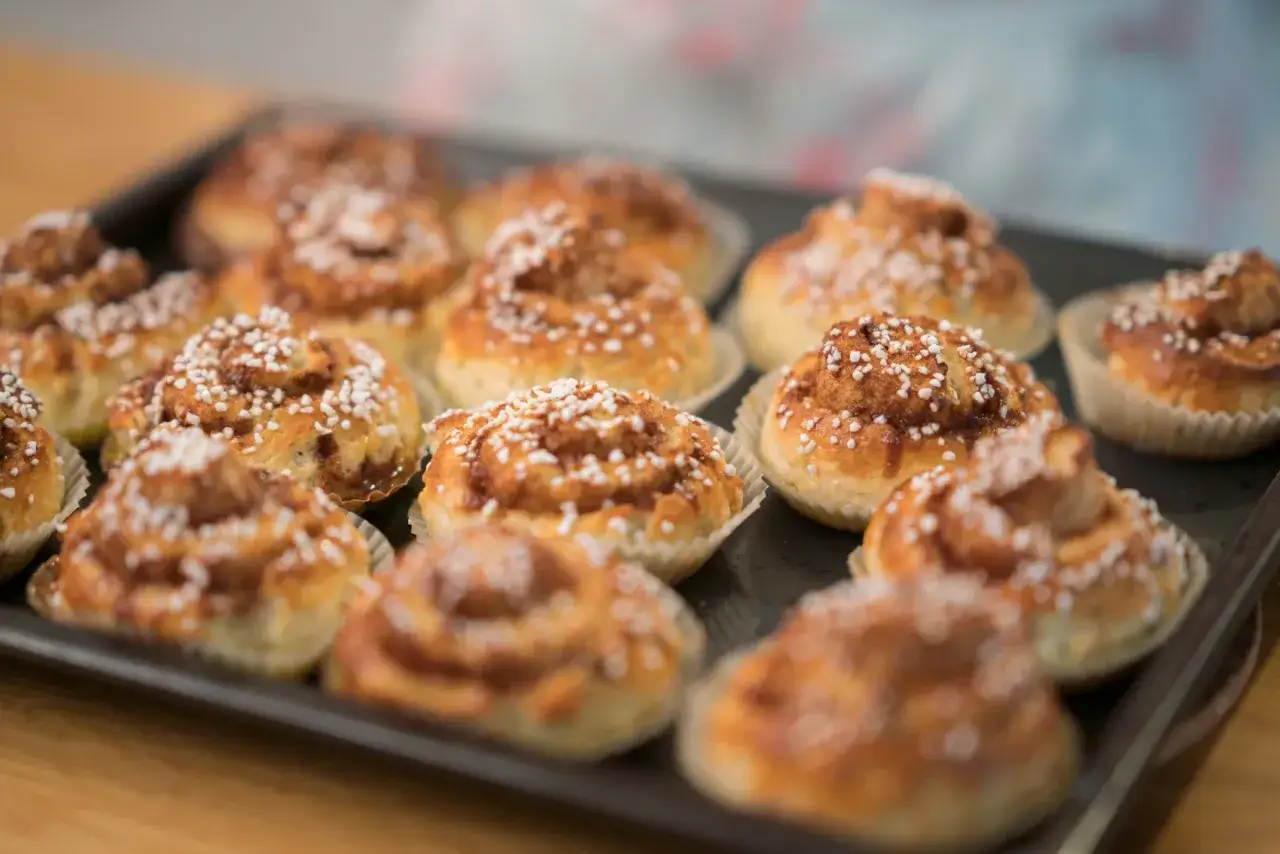 En bricka full med nybakade, gyllene glutenfria bullar, toppade med p&auml;rlsocker. Perfekt f&ouml;r fikat!