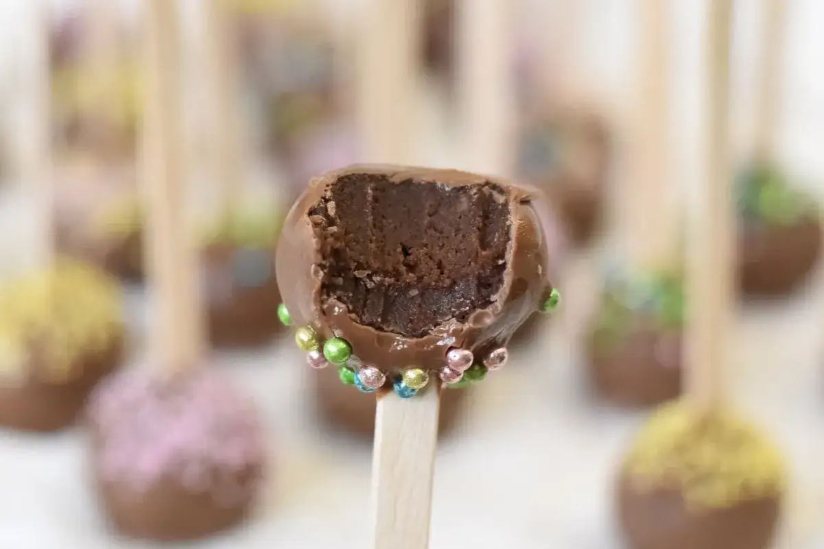 Chokladiga cake pops med f&auml;rgglada str&ouml;ssel. En &auml;r upp&auml;ten och visar det saftiga inkr&aring;met.