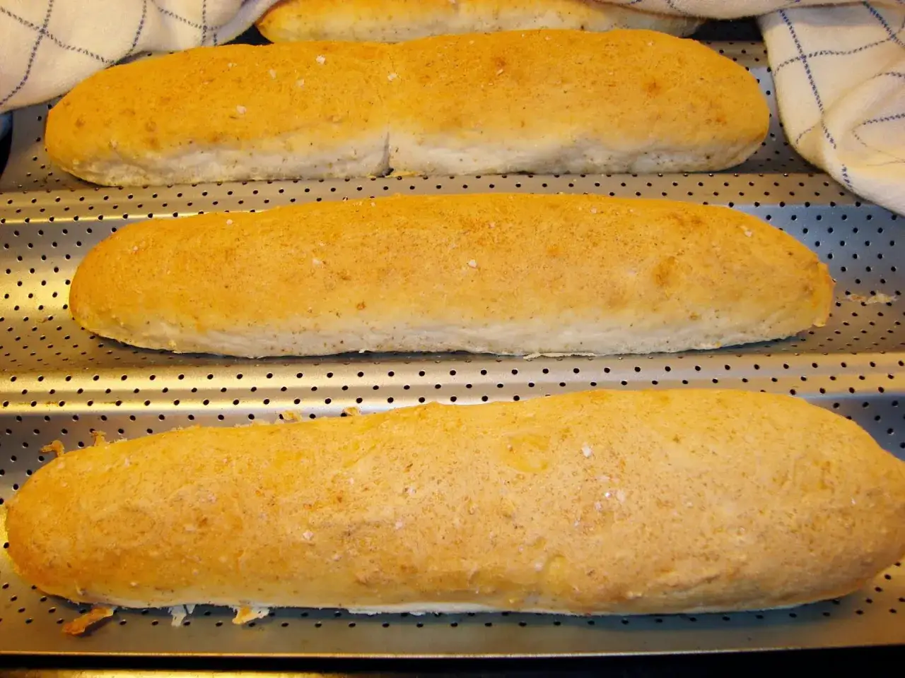 Nybakade, gyllene glutenfria baguetter p&aring; en perforerad pl&aring;t. Ett perfekt glutenfria baguetter recept f&ouml;r hembakat br&ouml;d.
