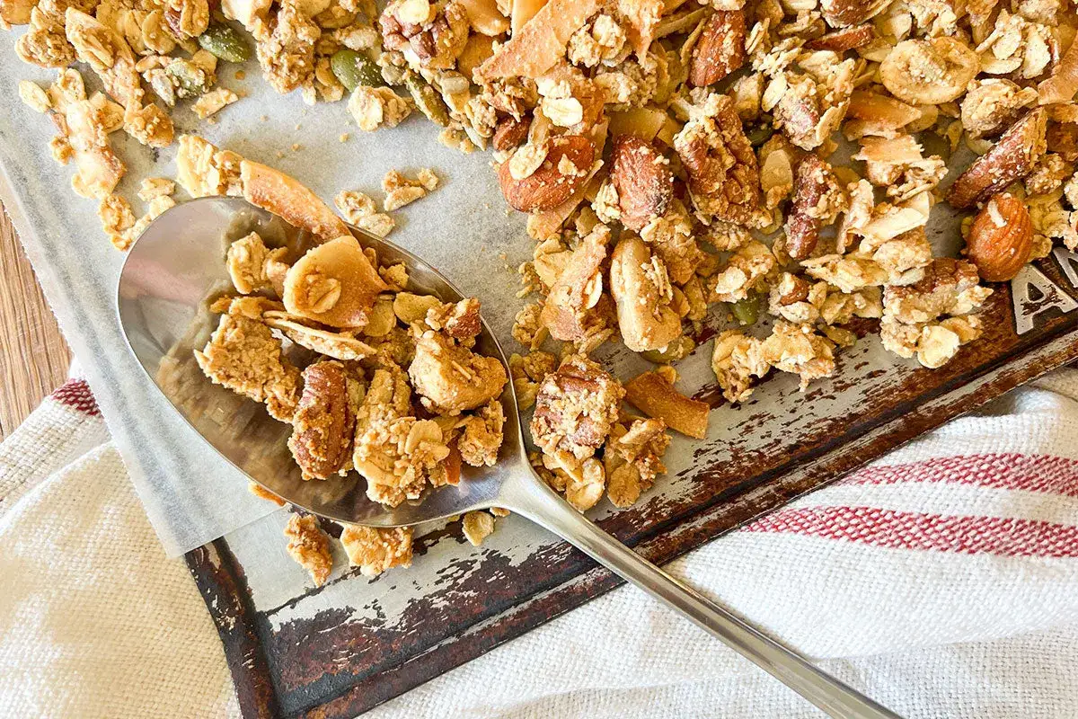 En sked full med hemgjord glutenfri granola med n&ouml;tter och kokosflingor. Ett perfekt glutenfri granola recept f&ouml;r frukost eller mellanm&aring;l.