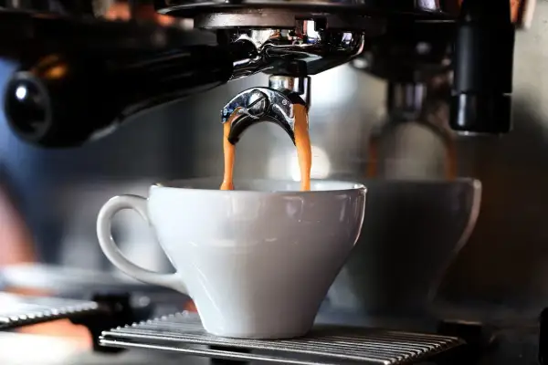 En liten espresso rinner ner i en vit kopp från en espressomaskin.