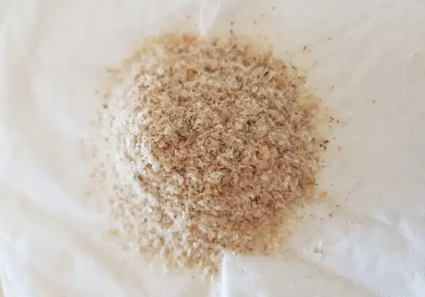 En hög med fiberhusk psyllium på vitt papper.