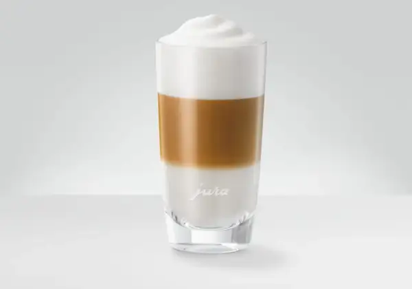 En perfekt lagerdelad latte macchiato i ett glas med Jura-logotyp.