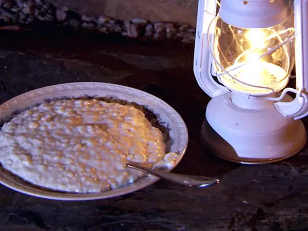 En skål med krämig risgrynspudding med bittermandel, belyst av en vit oljelampa.
