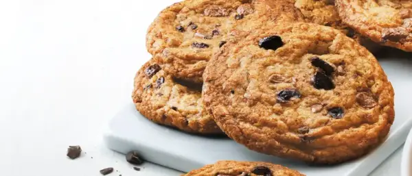 En hög med gyllene, glutenfria chocolate chip cookies, perfekta för en fika.