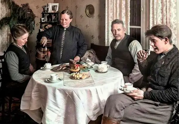 En familj samlas runt ett dukat bord för att dricka kaffe. En kvinna häller upp kaffe, en annan tittar ner, medan två män sitter och samtalar. En scen som speglar kaffe historia i Sverige.