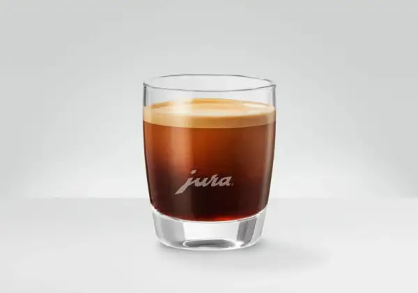 En perfekt dubbel espresso med gyllene crema i ett elegant glas med Jura-logotypen.