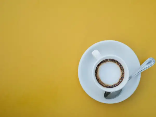 En kopp kaffe macchiato med skum och en ring av kaffe på en gul bakgrund. Perfekt för ett enkelt macchiato recept.